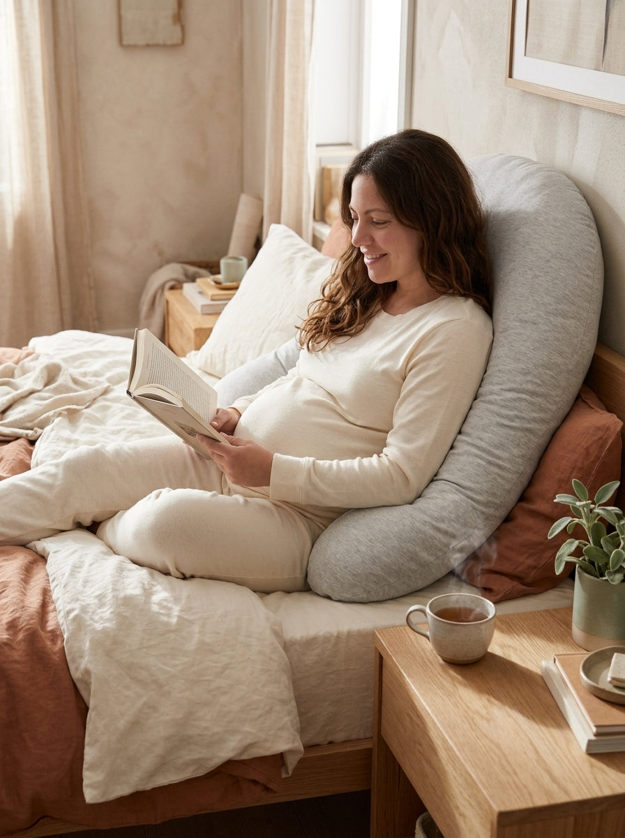 femme enceinte qui lit au lit, adossée au coussin